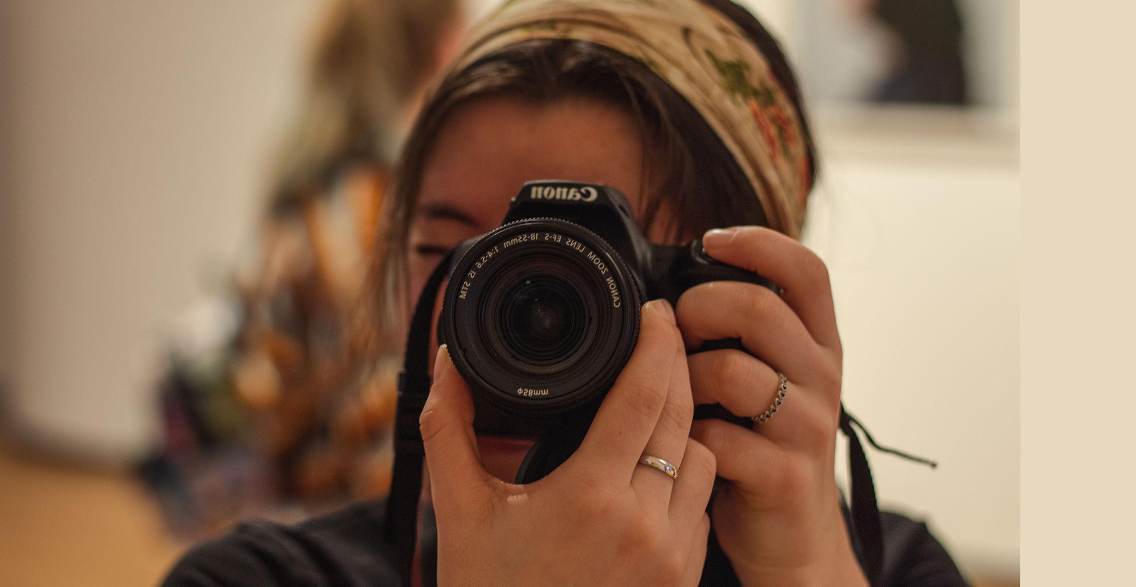 A Carthage College's photography major using a camera.